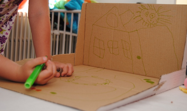 Kind tekent een speelstad op een kartonnen doos